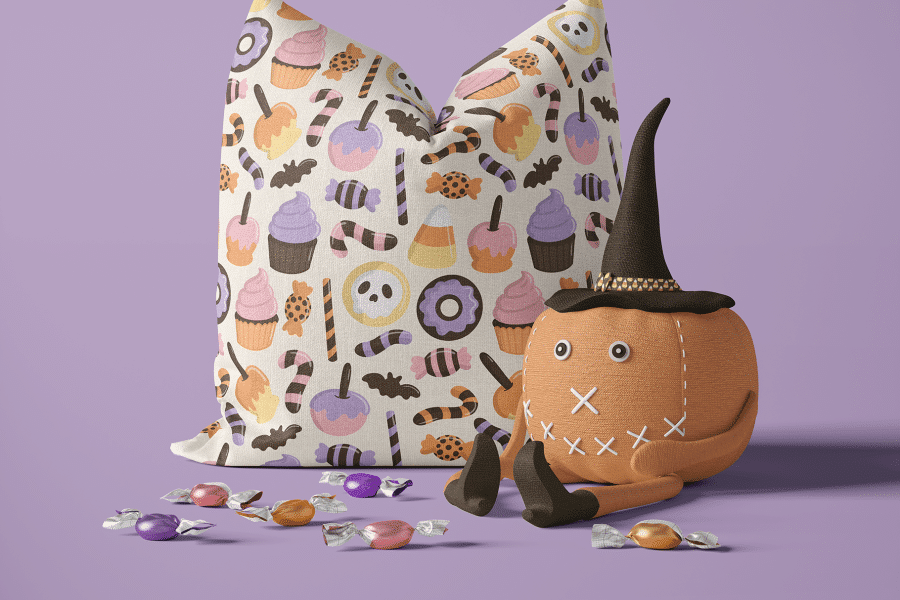 Halloween Pillow With Candy Pattern And A Small Pumpkin Wearing A Witch'S Hat.