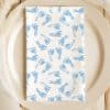 A White Napkin With A Pattern Of Light Blue Baby Footprints On A Beige Plate.