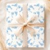 A Gift Wrapped In White Paper With A Pattern Of Light Blue Baby Footprints And Tied With A Beige Ribbon.