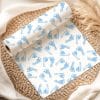 A Roll Of Baby Blue Footprint Patterned Wrapping Paper Sits On A Woven Placemat.