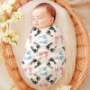 Sleeping Newborn Swaddled In A Blanket With Pink, Blue, And Black Footprints.