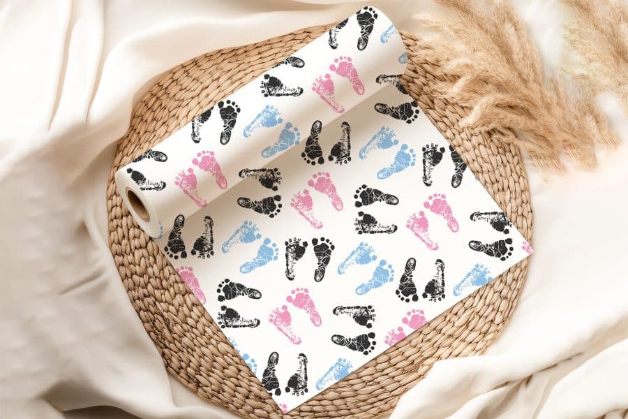 A Roll Of Wrapping Paper With A Pattern Of Pink, Blue, And Black Baby Footprints.