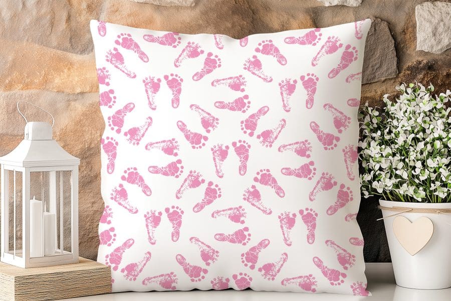 White Pillow With A Repeating Pattern Of Pink Baby Footprints.