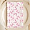 A White Napkin With A Pink Baby Footprint Pattern On A Beige Plate.