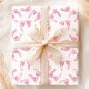 A Gift Wrapped In Pink Baby Footprints Wrapping Paper With A Beige Ribbon.