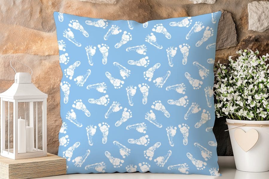Light Blue Square Pillow With A Pattern Of White Baby Footprints.