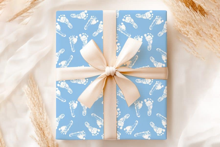 Light Blue Gift Box With A Beige Ribbon, Wrapped In Baby Footprints Pattern.