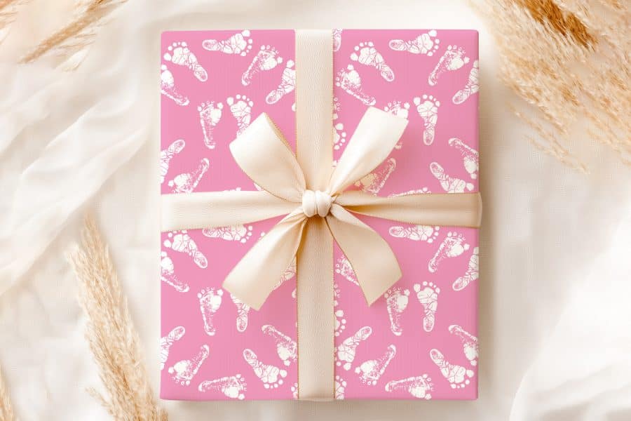 Pink Gift Box With A Beige Ribbon, Wrapped In Baby Footprints Design.
