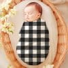 Sleeping Baby Wrapped In A Black And White Buffalo Plaid Swaddle.