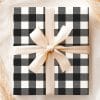 A Gift Wrapped In Black And White Buffalo Plaid With A Beige Ribbon.