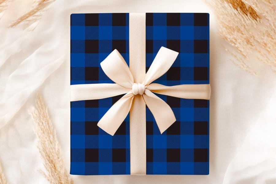 A Blue And Black Plaid Gift Box With A Beige Ribbon.