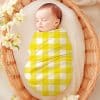 Sleeping Baby Swaddled In A Yellow And White Gingham Blanket.