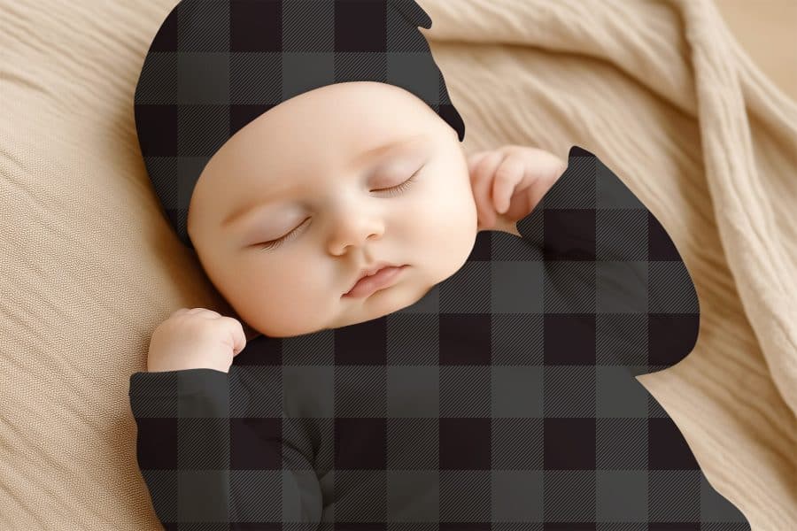 Sleeping Baby Wearing A Dark Gray And Black Plaid Onesie And Matching Hat.