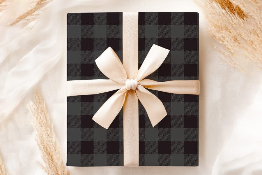 A Black And Gray Plaid Gift Box With A Beige Ribbon.