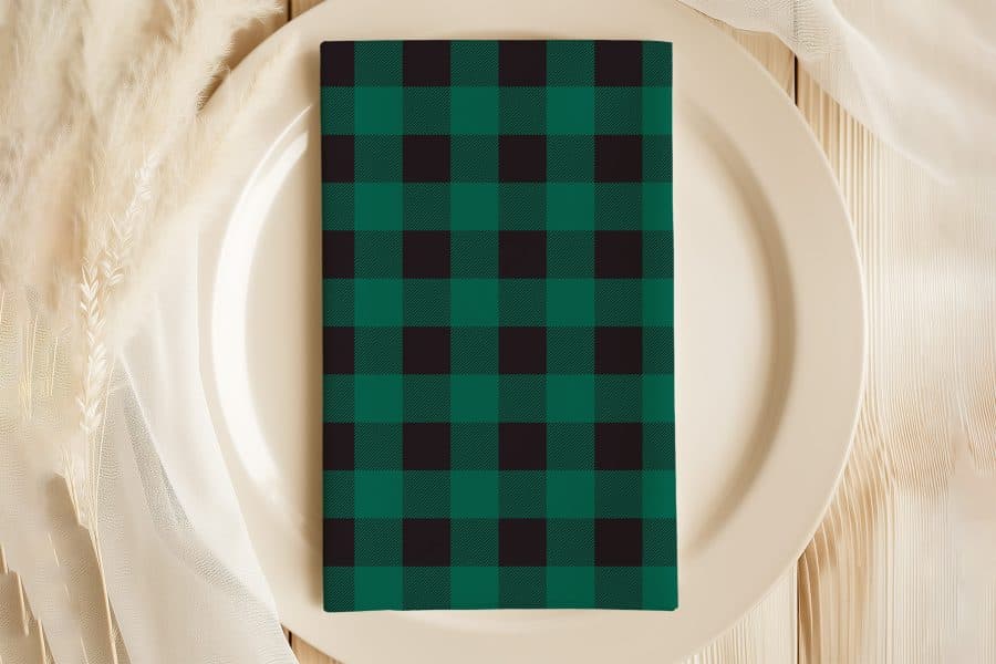 Green And Black Buffalo Plaid Napkin On A White Plate.