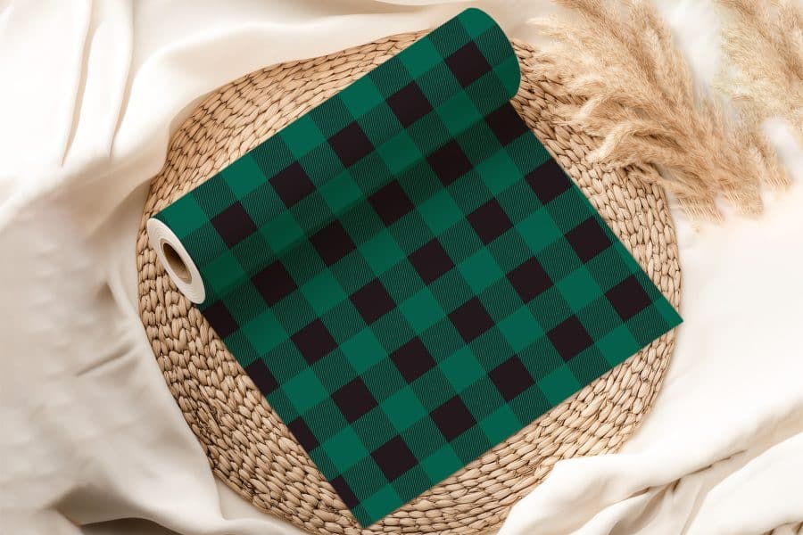 Roll Of Dark Green And Black Buffalo Plaid Fabric On A Woven Placemat.
