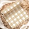 Beige And White Gingham Patterned Wrapping Paper Roll On A Woven Mat.
