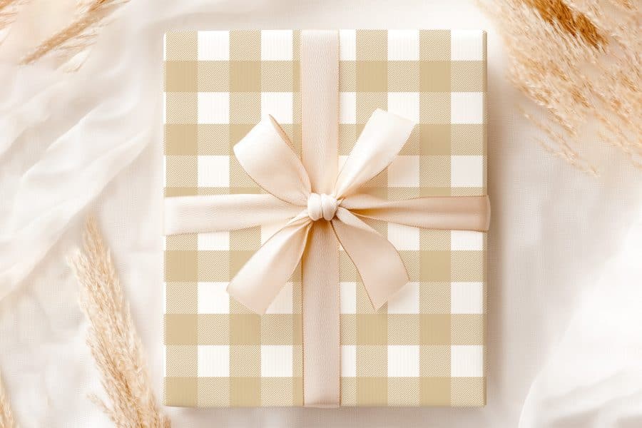 Beige And White Gingham Gift Box With A Beige Ribbon Tied In A Bow.