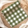 A Roll Of Olive Green And White Gingham Fabric On A Woven Placemat.
