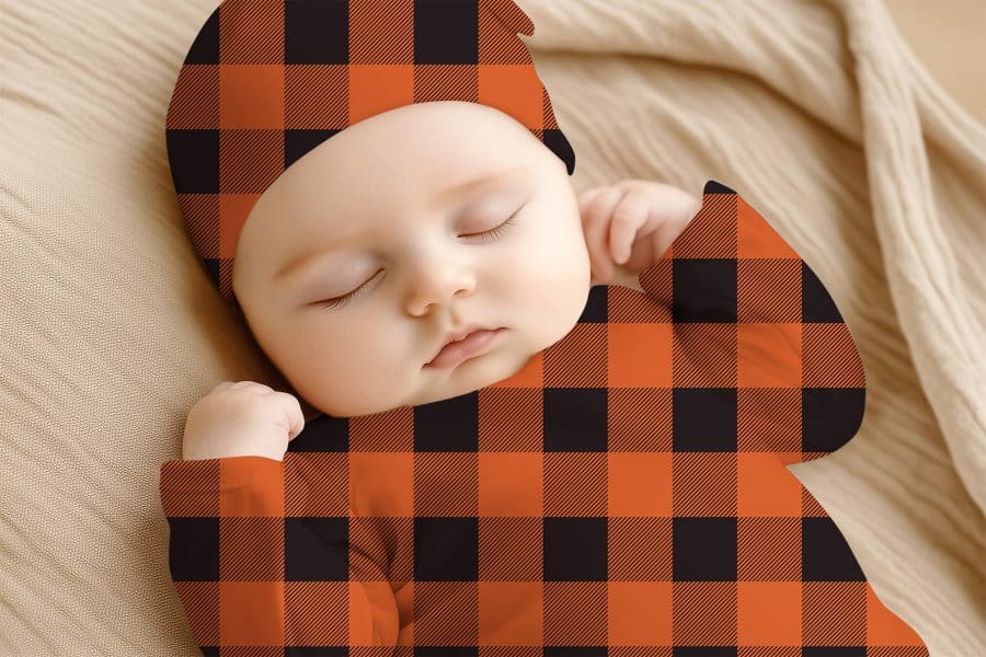 Sleeping Baby Wearing An Orange And Black Buffalo Plaid Outfit.