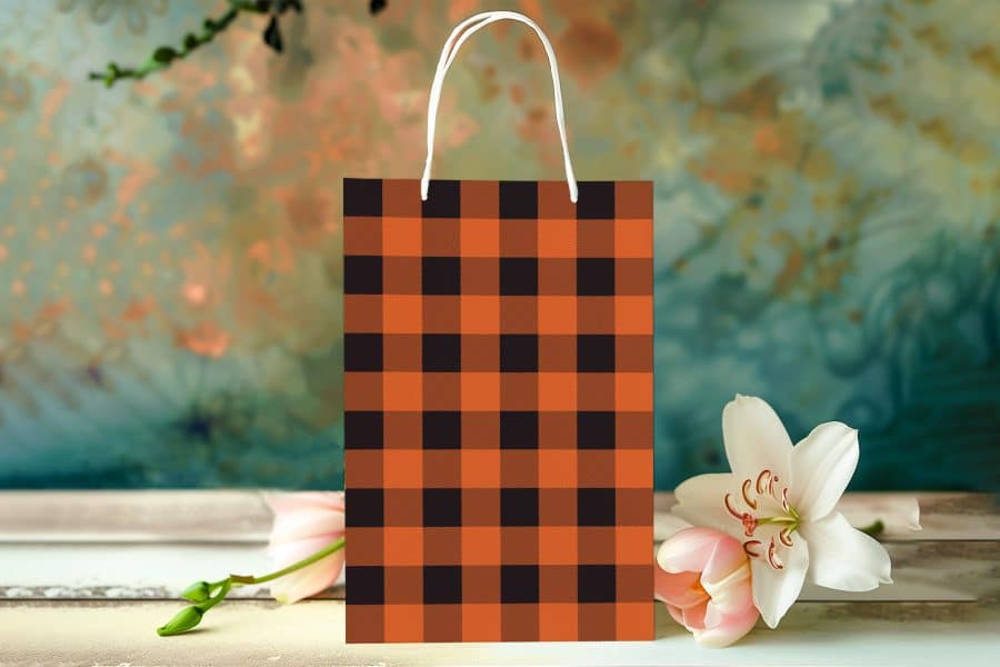 Orange And Black Buffalo Plaid Gift Bag With White Handles.