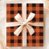 A Gift Wrapped In Orange And Black Buffalo Plaid With A Cream-Colored Ribbon.