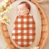 Sleeping Baby Swaddled In An Orange And White Gingham Blanket.