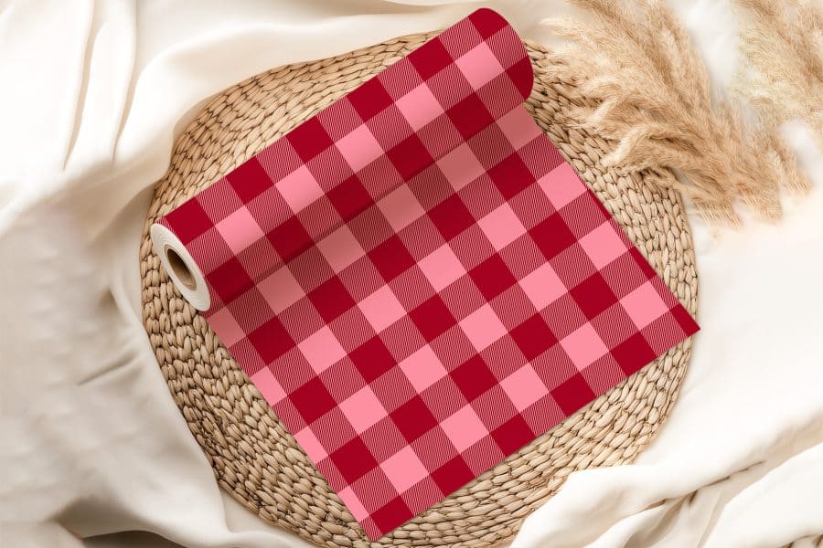 Roll Of Red And Pink Gingham Fabric On A Woven Mat.
