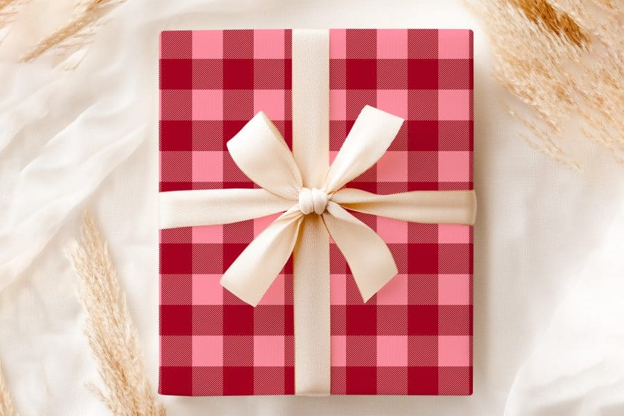 A Gift Box With A Red And Pink Plaid Pattern And A Cream-Colored Ribbon.