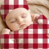 Sleeping Baby Wearing A Red And White Buffalo Plaid Outfit.