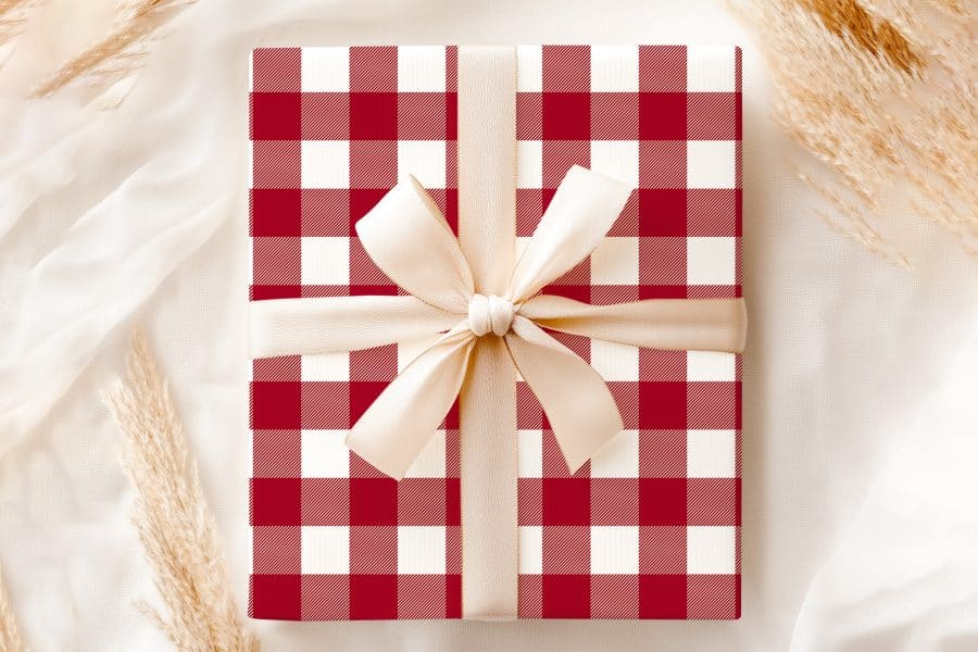 A Gift Wrapped In Red And White Gingham Paper With A Cream-Colored Ribbon.