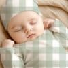 Sleeping Baby Wearing A Sage Green And White Gingham Patterned Outfit.