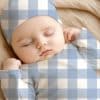 Sleeping Baby Wearing A Blue And White Gingham Outfit.