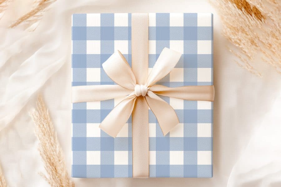 A Gift Box With A Light Blue And White Gingham Pattern And A Beige Ribbon.
