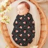 Sleeping Baby Swaddled In A Candy Corn Patterned Wrap.