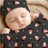 Sleeping Baby Wearing A Candy Corn Patterned Onesie And Hat.