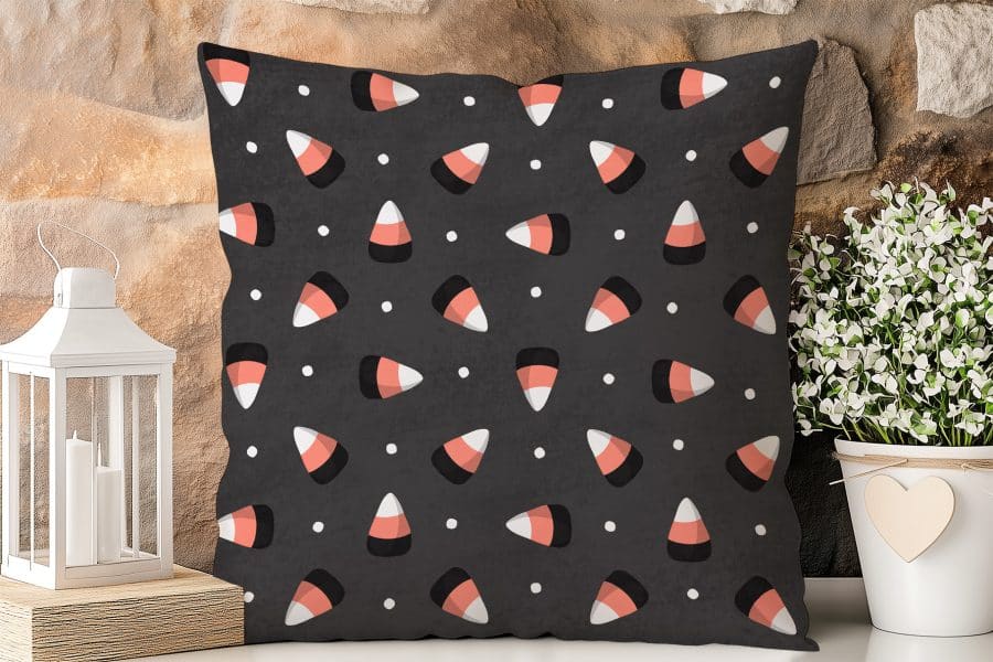 Dark Gray Square Pillow With A Repeating Pattern Of Orange And White Candy Corn.