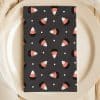 A Dark Gray Napkin With A Repeating Pattern Of Candy Corn Sits On A Beige Plate.
