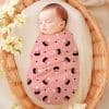 Sleeping Baby Swaddled In A Pink Candy Corn Patterned Blanket.