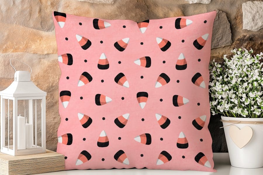 Pink Pillow With A Repeating Pattern Of Candy Corn.