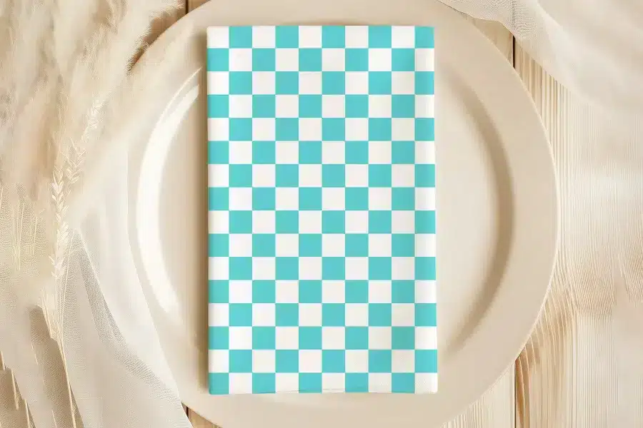 A Teal And White Checkered Napkin On A Beige Plate.