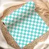A Roll Of Teal And White Checkered Wrapping Paper On A Woven Placemat.