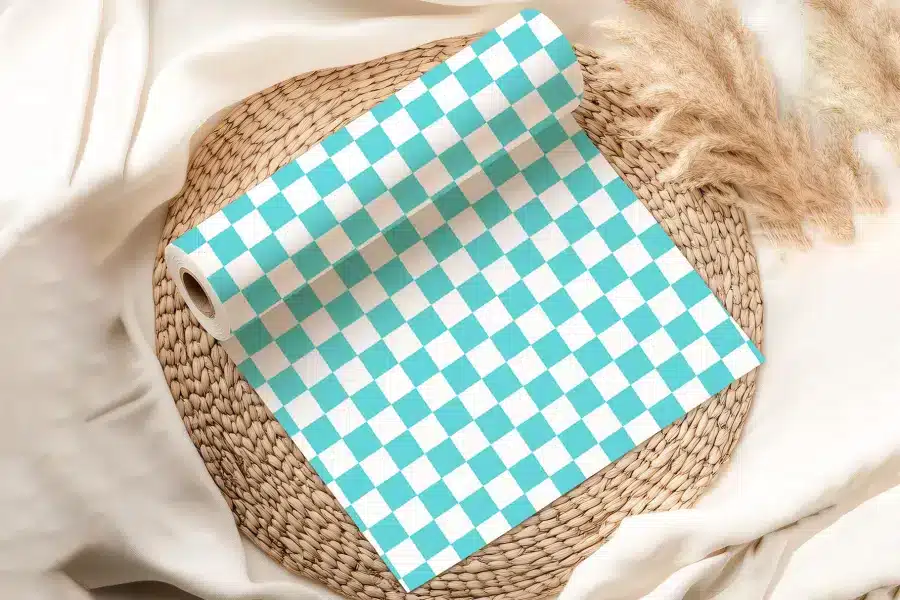 A Roll Of Teal And White Checkered Wrapping Paper On A Woven Placemat.