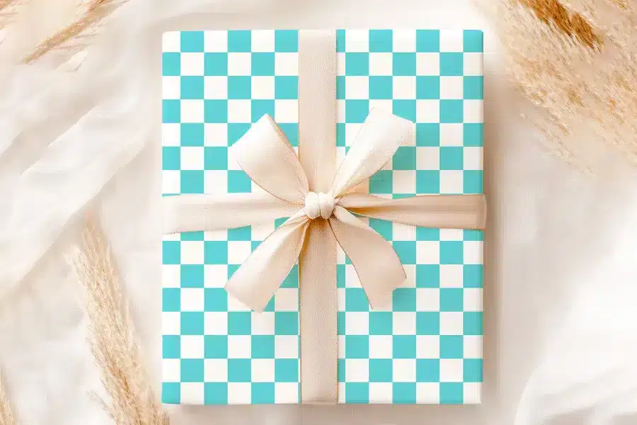 A Light Teal And White Checkered Gift Box With A Beige Ribbon.