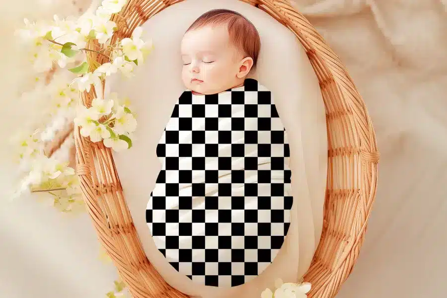 Sleeping baby swaddled in a black and white checkered wrap.