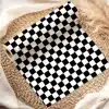 A Roll Of Black And White Checkered Paper Sits On A Woven Mat.