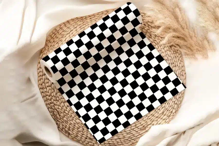 A Roll Of Black And White Checkered Paper Sits On A Woven Mat.
