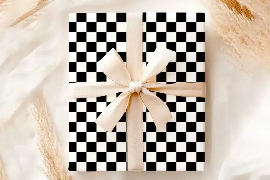 A Gift Box With A Black And White Checkered Pattern And A Beige Ribbon.