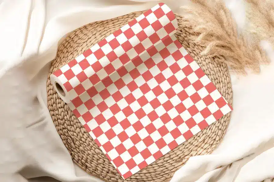 Coral And White Checkered Wrapping Paper Roll On A Woven Mat.