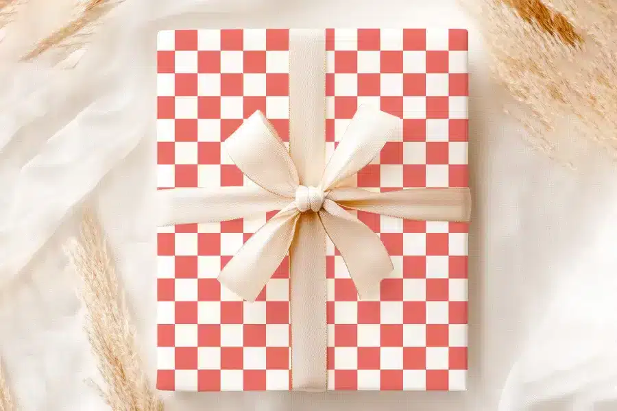 A Coral And White Checkered Gift Box With A Beige Ribbon.